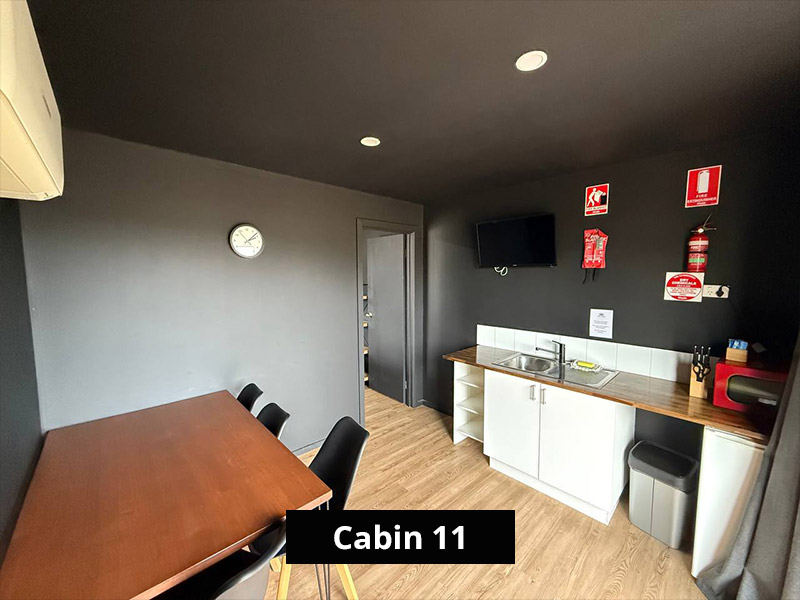 Compact kitchenette in Cabin 11 featuring sink, fridge, microwave and open shelving, ideal for short stays near the Grampians.